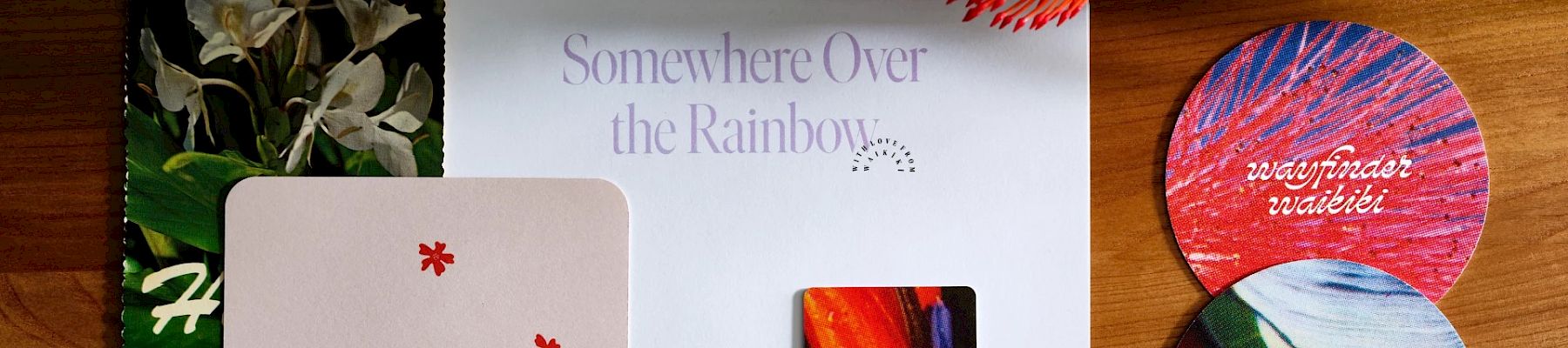 The image shows various colorful items including a card that says "Somewhere Over the Rainbow," a plant, and circular objects with vibrant designs.