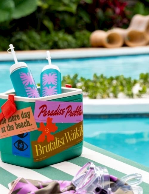 A colorful box of beach party supplies by a sunny pool, with flip-flops, drinks, and a &ldquo;Paradise Pool&rdquo; vibe, ready for a sunny day at the beach.