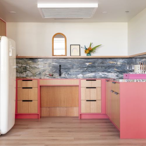 Eine kleine K&uuml;che besticht durch farbenfrohe Schr&auml;nke, eine Marmor-R&uuml;ckwand, einen Vintage-K&uuml;hlschrank und moderne Dekoration auf der Arbeitsfl&auml;che und an den W&auml;nden.