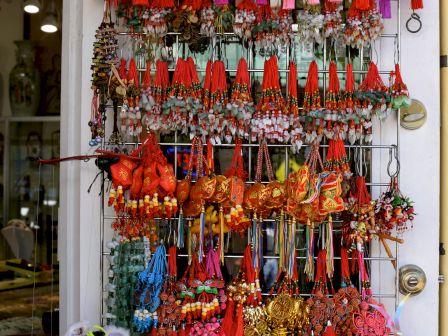 Colorful market rack of dangling accessories&mdash;red tassels, beads, charms, and wrist/neck jewelry on display.